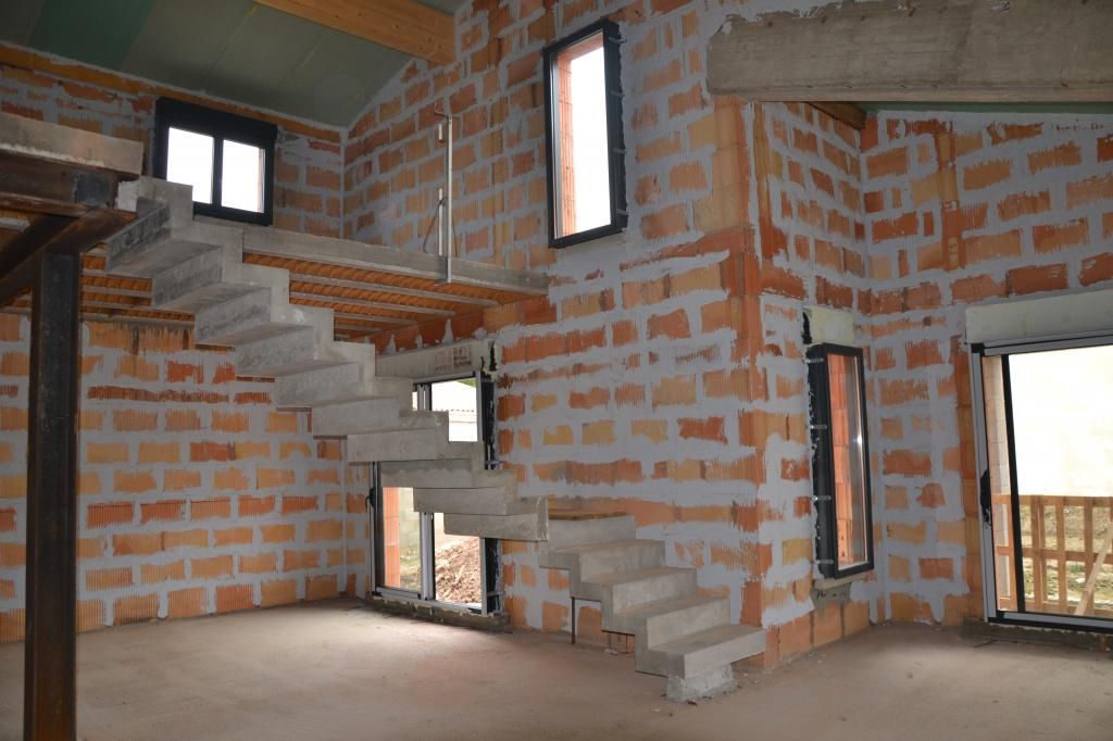 Intérieur brut d'une construction neuve, murs en briques et escalier béton à Montélimar